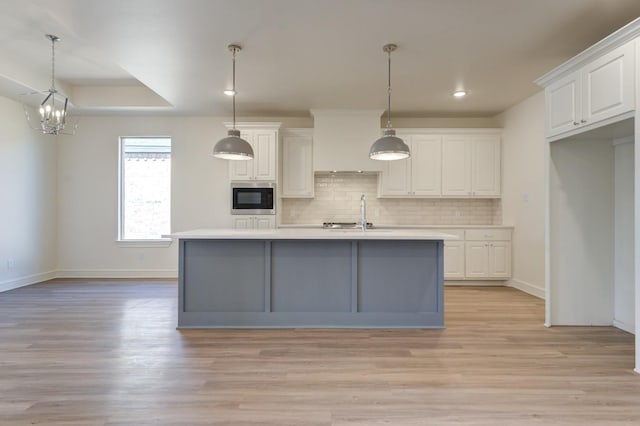 kitchen with white cabinetry, pendant lighting, and a center island with sink