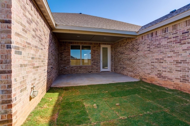 entrance to property featuring a yard and a patio area