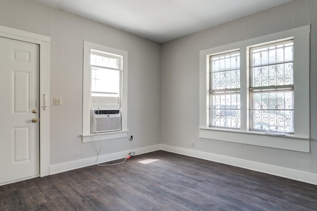 empty room featuring cooling unit, dark hardwood / wood-style floors, and a wealth of natural light