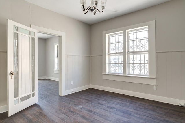 empty room featuring a notable chandelier and dark hardwood / wood-style floors