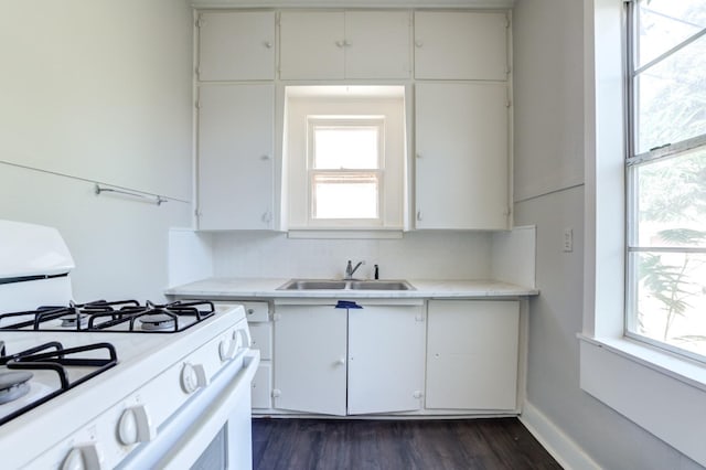 kitchen with white gas range, dark wood-type flooring, sink, and white cabinets