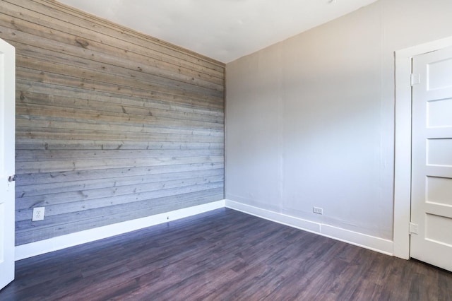 empty room with dark hardwood / wood-style floors and wooden walls