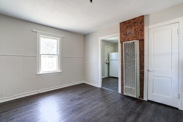 unfurnished bedroom with dark wood-type flooring, a closet, and white refrigerator