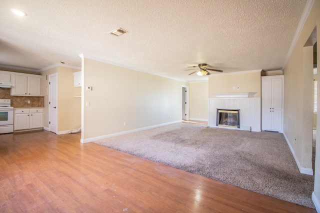 unfurnished living room featuring crown molding, light hardwood / wood-style flooring, ceiling fan, a fireplace, and a textured ceiling