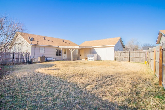 back of house with central AC unit and a lawn