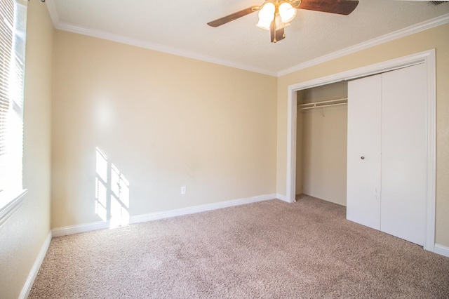 unfurnished bedroom featuring crown molding, carpet, ceiling fan, and a closet