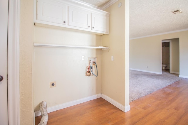 washroom with electric dryer hookup, light hardwood / wood-style flooring, ornamental molding, and a textured ceiling