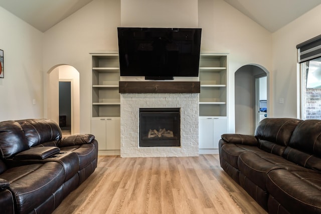 living room featuring a stone fireplace, light hardwood / wood-style flooring, and high vaulted ceiling