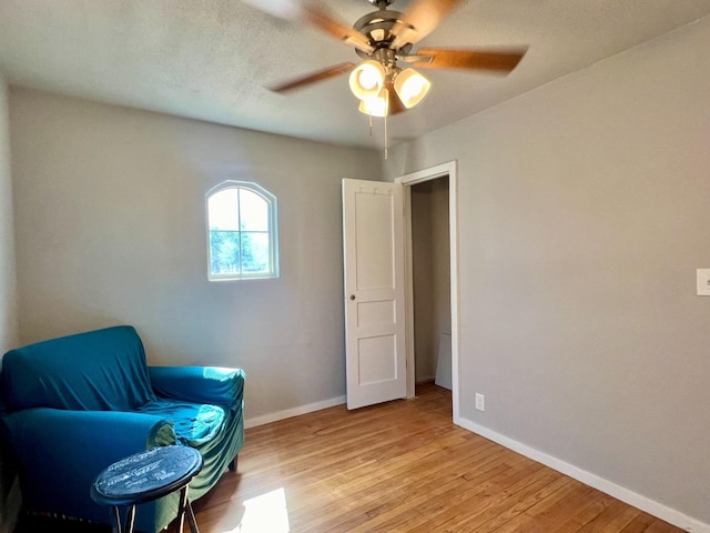 sitting room with ceiling fan and light wood-type flooring