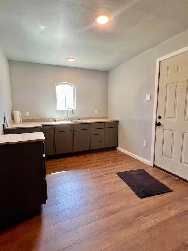 kitchen with sink, light hardwood / wood-style flooring, and a textured ceiling