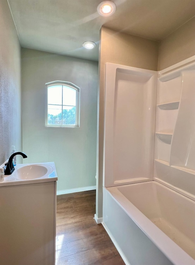 bathroom featuring wood-type flooring, vanity, and washtub / shower combination