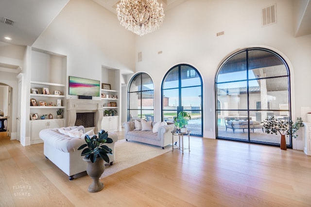 living room with an inviting chandelier, light hardwood / wood-style floors, and built in features