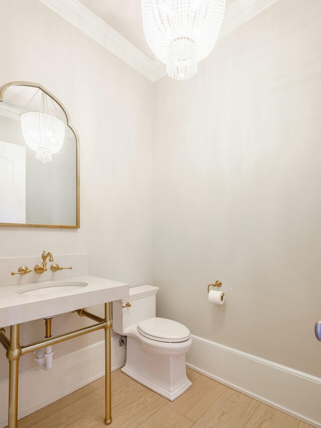 bathroom featuring an inviting chandelier, sink, ornamental molding, and toilet