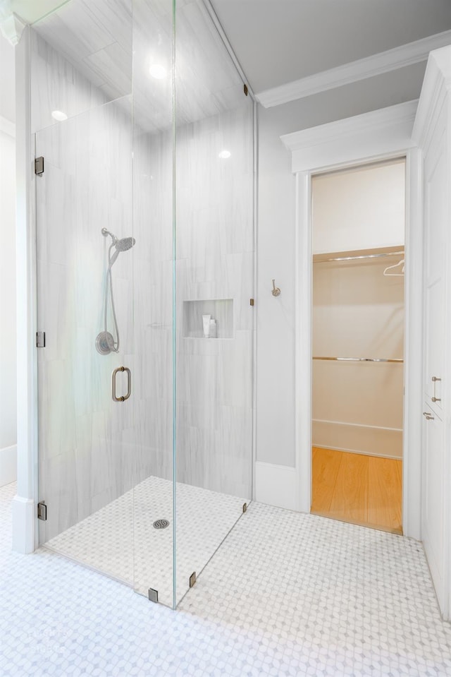 bathroom with a shower with door and ornamental molding