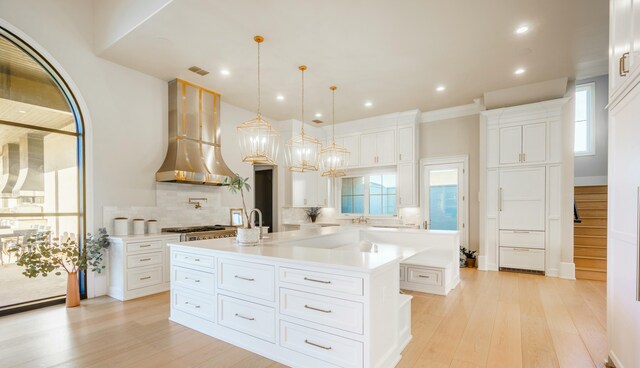 kitchen with a spacious island, pendant lighting, white cabinets, and range hood