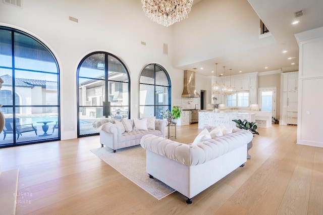 living room featuring an inviting chandelier, light hardwood / wood-style floors, and a high ceiling