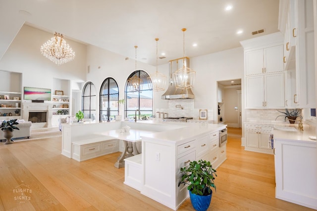 kitchen featuring white cabinetry, decorative light fixtures, light hardwood / wood-style flooring, stainless steel appliances, and a large island