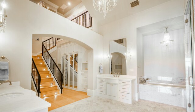 interior space featuring vanity, a towering ceiling, independent shower and bath, and a chandelier