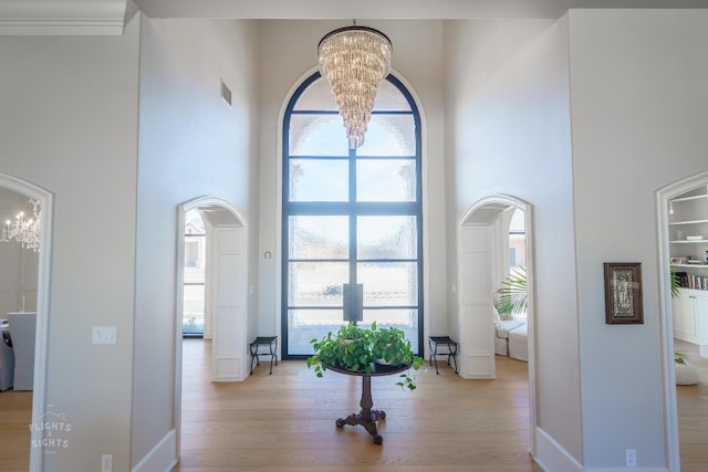 foyer entrance with a wealth of natural light, a chandelier, and light hardwood / wood-style flooring