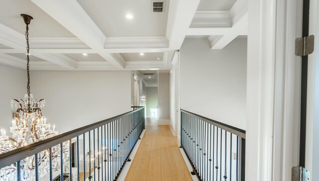 corridor featuring coffered ceiling, wood-type flooring, a chandelier, ornamental molding, and beam ceiling