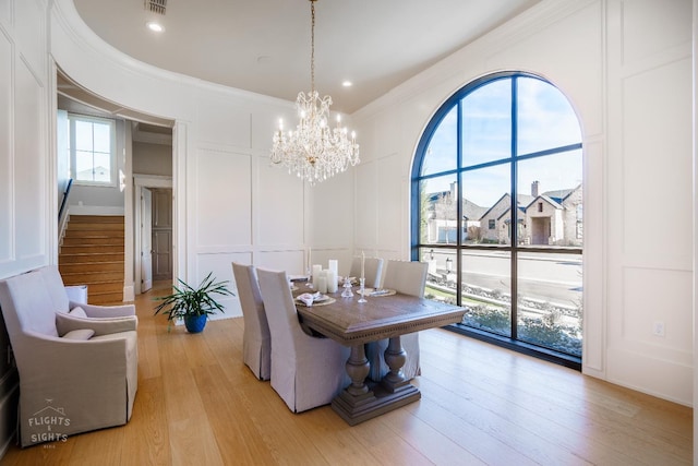 dining area with a notable chandelier, light hardwood / wood-style flooring, and ornamental molding