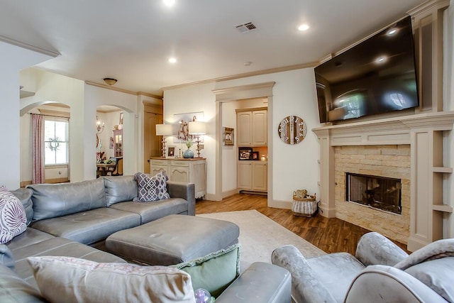 11507 Topeka Ave, Lubbock, TX 79424 - living room with arched walkways, light wood finished floors, a fireplace, recessed lighting, and crown molding