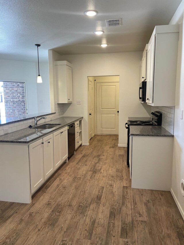 kitchen with sink, white cabinetry, hanging light fixtures, black appliances, and dark hardwood / wood-style flooring