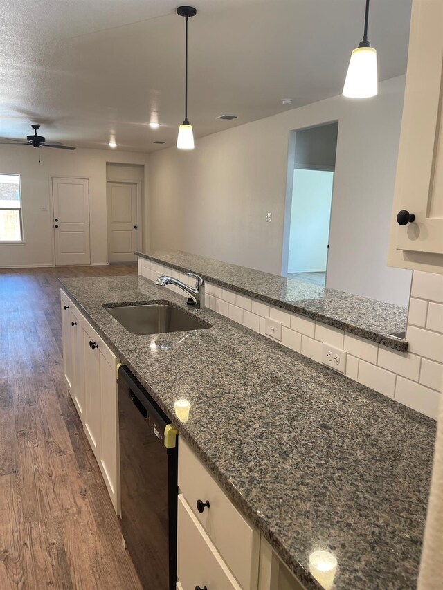 kitchen featuring sink, white cabinetry, decorative light fixtures, dishwasher, and dark stone counters