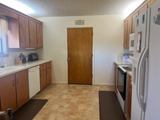 kitchen with sink, white appliances, and a textured ceiling