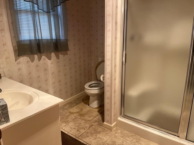 bathroom featuring tile patterned flooring, vanity, toilet, and walk in shower