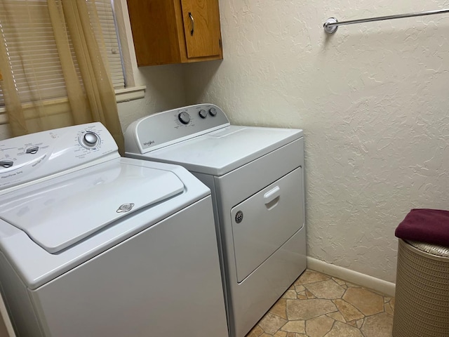 clothes washing area featuring cabinets and washer and dryer