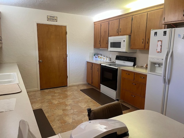 kitchen with sink, a textured ceiling, and white appliances