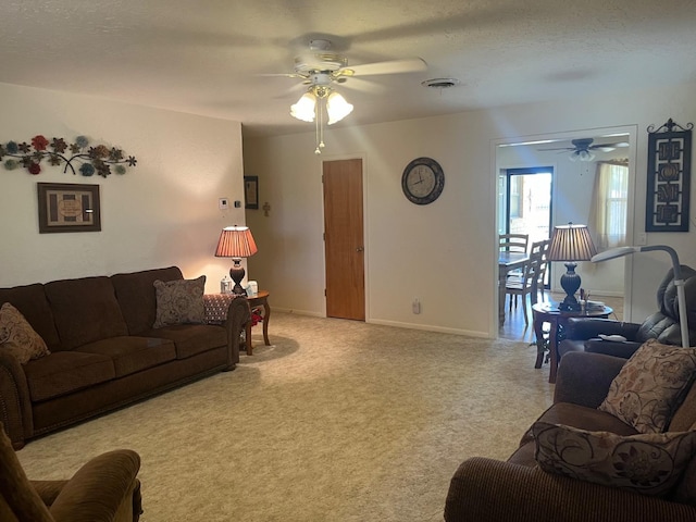 living room with ceiling fan, light carpet, and a textured ceiling