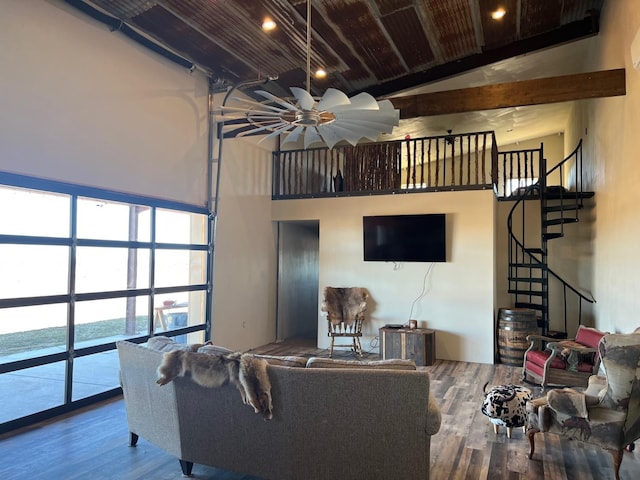 living room with wood-type flooring, a towering ceiling, and beam ceiling