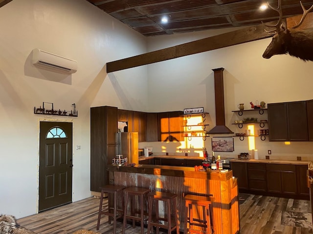 kitchen with high vaulted ceiling, wall chimney range hood, a kitchen breakfast bar, and an AC wall unit