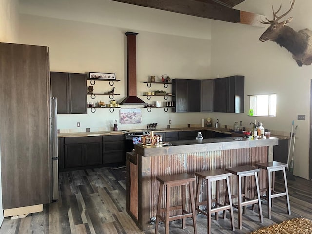 kitchen with dark hardwood / wood-style flooring, appliances with stainless steel finishes, a towering ceiling, and a kitchen breakfast bar