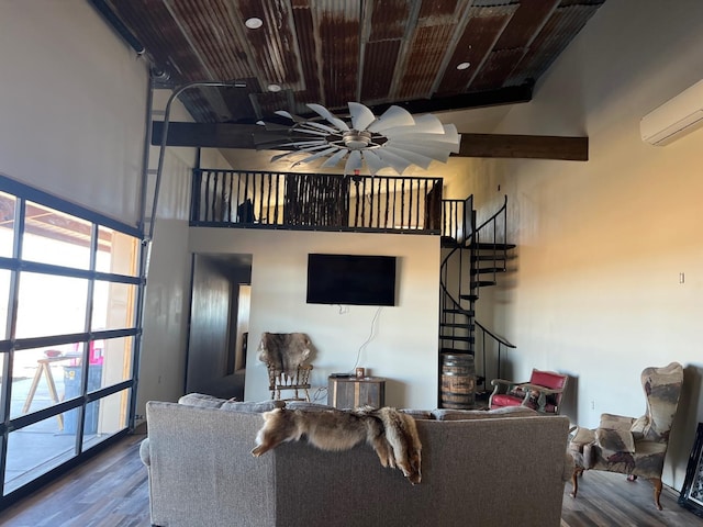 living room with hardwood / wood-style flooring, a wall mounted AC, ceiling fan, and a towering ceiling