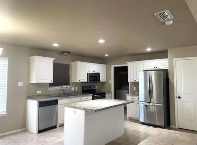 kitchen featuring sink, white cabinetry, appliances with stainless steel finishes, a kitchen island, and light stone countertops