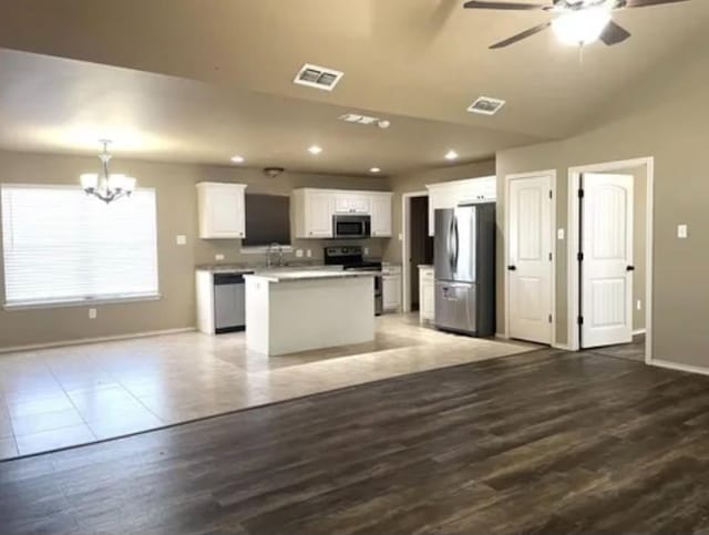 kitchen featuring pendant lighting, white cabinetry, appliances with stainless steel finishes, a kitchen island, and hardwood / wood-style flooring