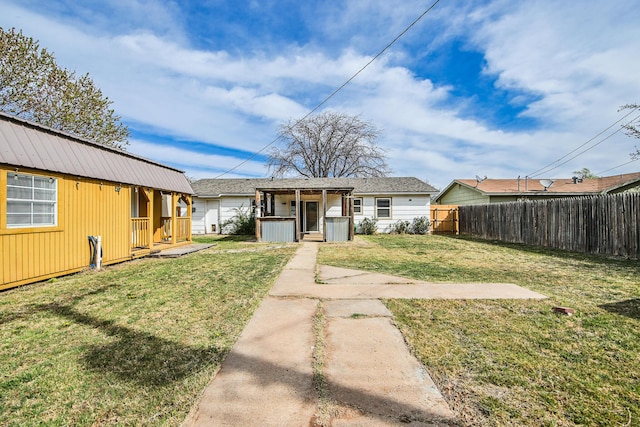 bungalow-style home with an outdoor structure, a front lawn, and fence