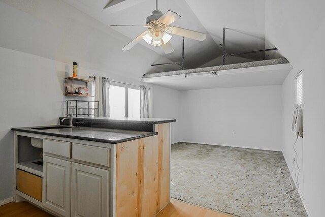 kitchen featuring a sink, ceiling fan, dark countertops, wood finished floors, and lofted ceiling