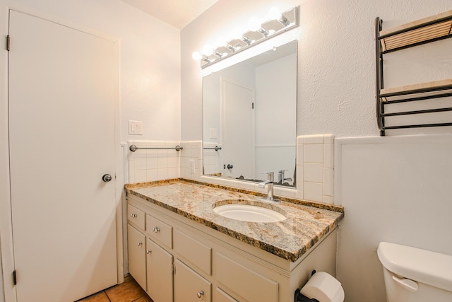 bathroom featuring radiator, vanity, toilet, wainscoting, and tile patterned floors