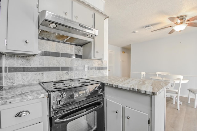 kitchen featuring a peninsula, a ceiling fan, under cabinet range hood, decorative backsplash, and black range with electric cooktop