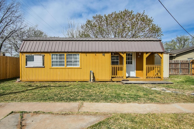 view of front of property featuring a front yard, a fenced backyard, metal roof, and an outbuilding