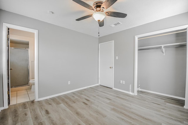 unfurnished bedroom with visible vents, baseboards, a closet, ensuite bath, and wood finished floors