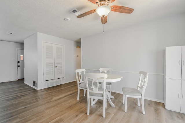 dining room with visible vents, ceiling fan, wood finished floors, and a textured ceiling