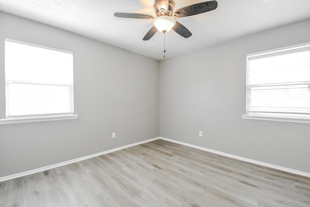 unfurnished room with a textured ceiling, light wood-type flooring, baseboards, and ceiling fan