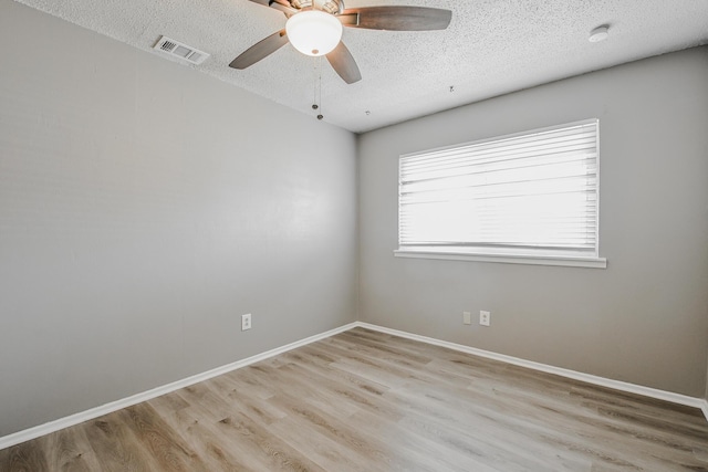 empty room with a textured ceiling, wood finished floors, and visible vents