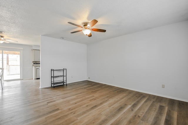 spare room featuring a textured ceiling, wood finished floors, a ceiling fan, and visible vents