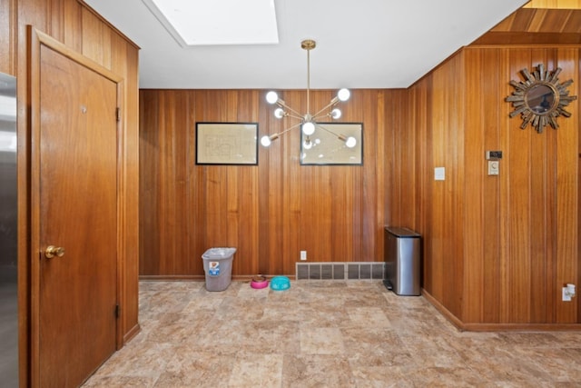 unfurnished dining area with a skylight and wood walls